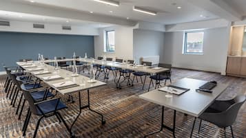Una sala de conferencias con mesas largas, sillas y piso alfombrado.