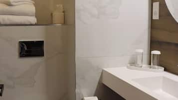 A bathroom with a toilet, sink, and mirror.