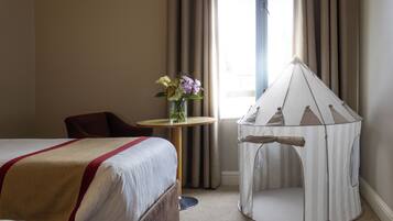 Une chambre d’hôtel avec un lit, une petite table sur laquelle est posé un vase de fleurs, une chaise et une structure ressemblant à une tente.