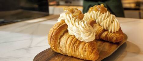 Deux croissants garnis de crème fouettée, présentés sur une planche en bois.