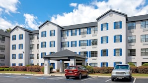 A multi-story hotel with a central entrance, parking spaces, and blue window shutters. - InTown Suites Extended Stay Atlanta GA - Marietta Town Center (Marietta)