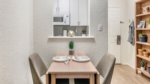 Una cocina compacta con armarios blancos, un microondas y una pequeña ventana sobre la encimera.