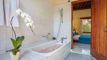 Un bagno con vasca, doccia e un'orchidea in vaso.
