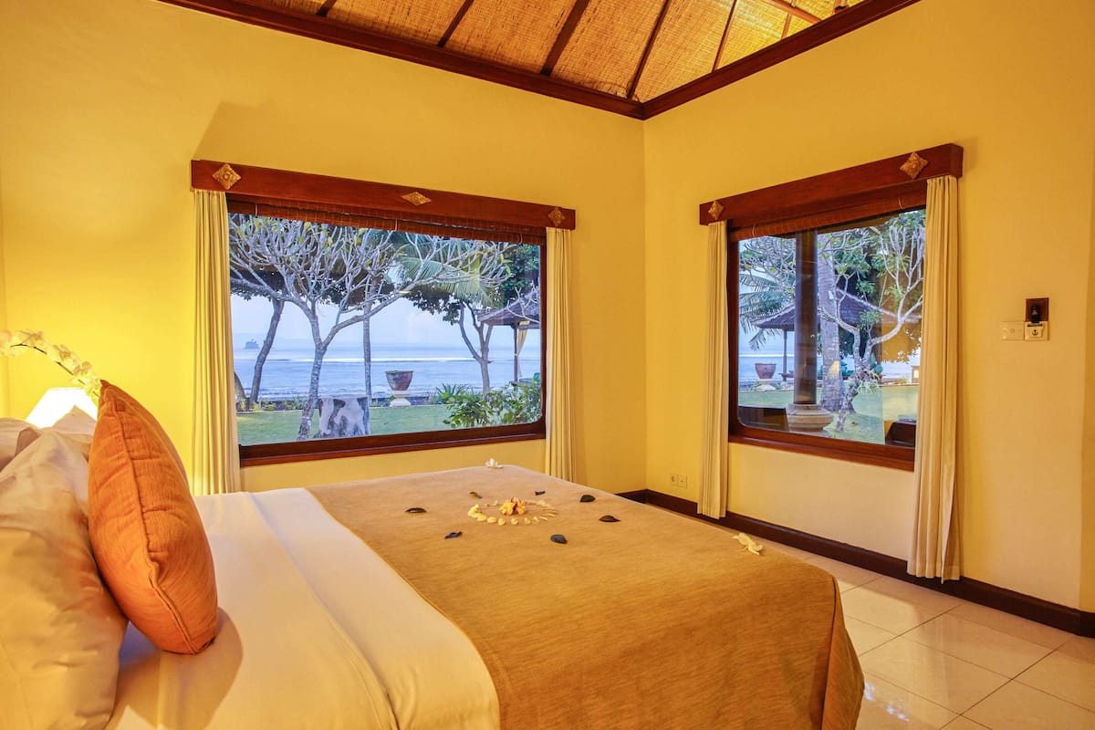 Ein Hotelzimmer mit Bett, Fenster und Meerblick, eingebettet in eine tropische Landschaft.