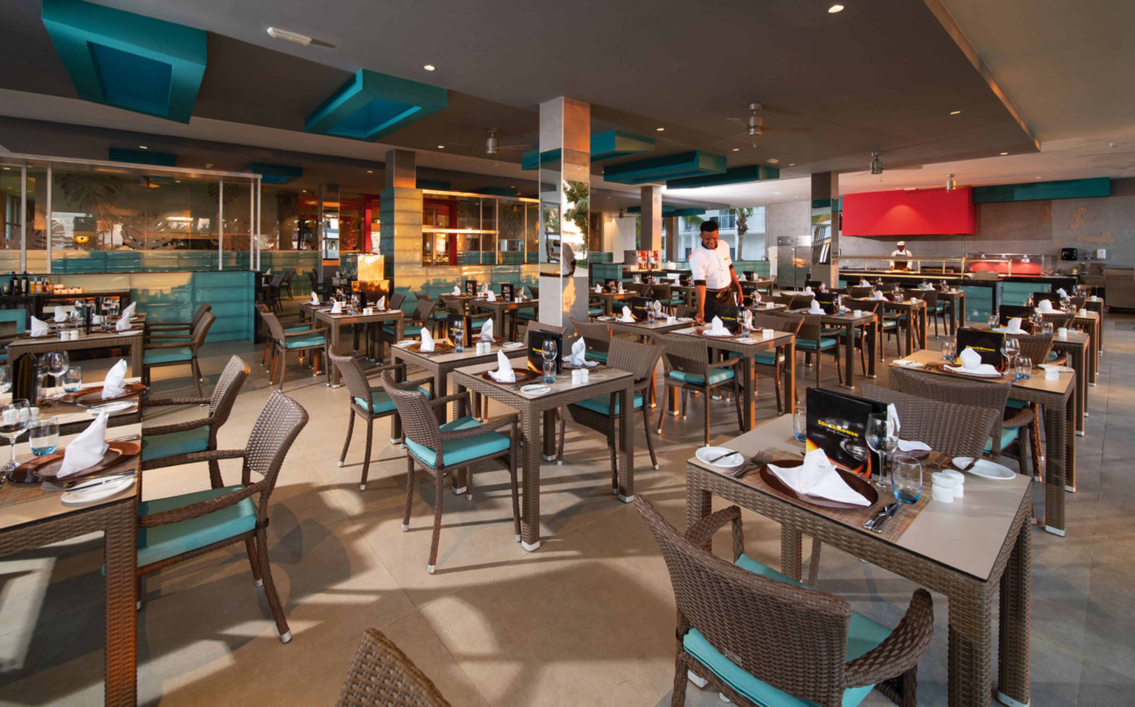 Ein geräumiges Restaurant mit mehreren Essbereichen, Korbstühlen und einem modernen Innenraum.
