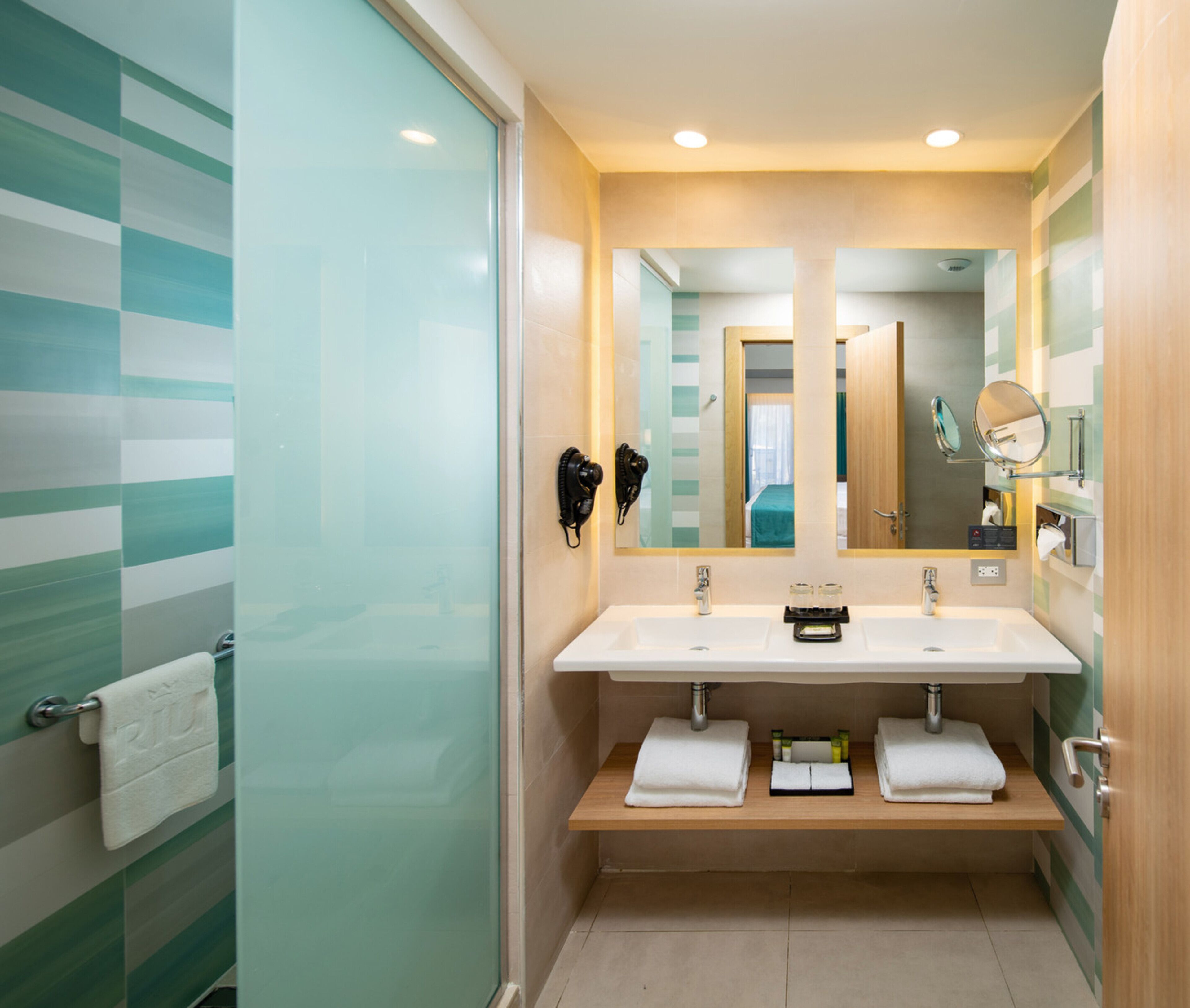 A modern bathroom with a glass shower enclosure, a double sink vanity, and a large mirror above the sink.