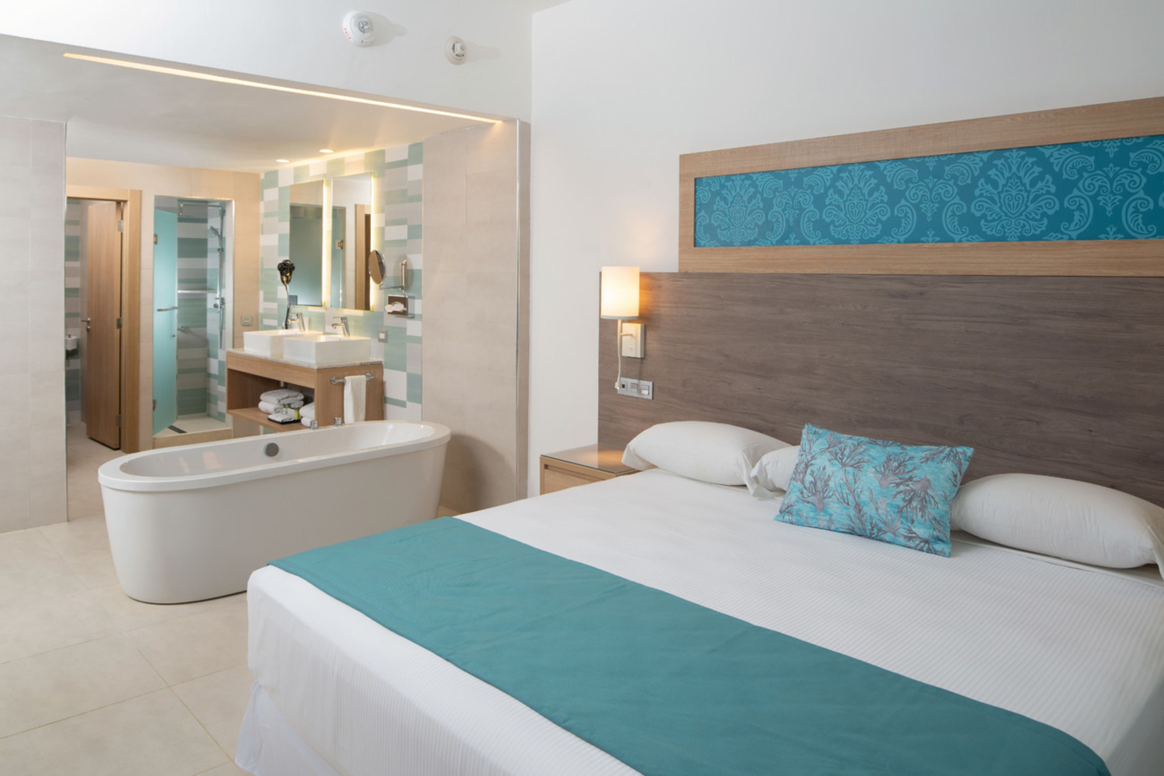 Una habitación de hotel moderna con una cama grande, una bañera y un baño separado.