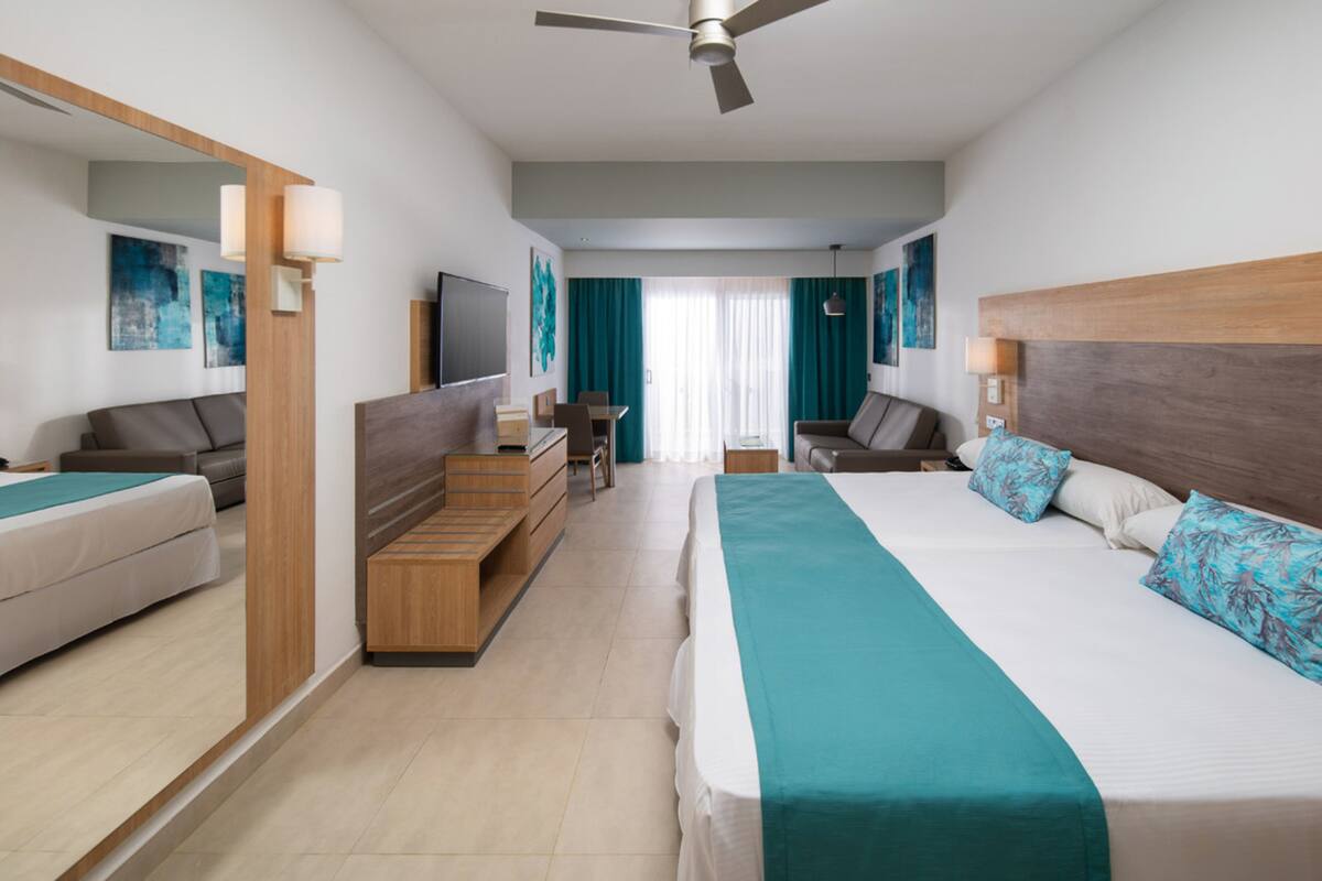 Ein modernes Hotelzimmer mit einem großen Bett, einem Schreibtisch, einer Couch und einem Fernseher.