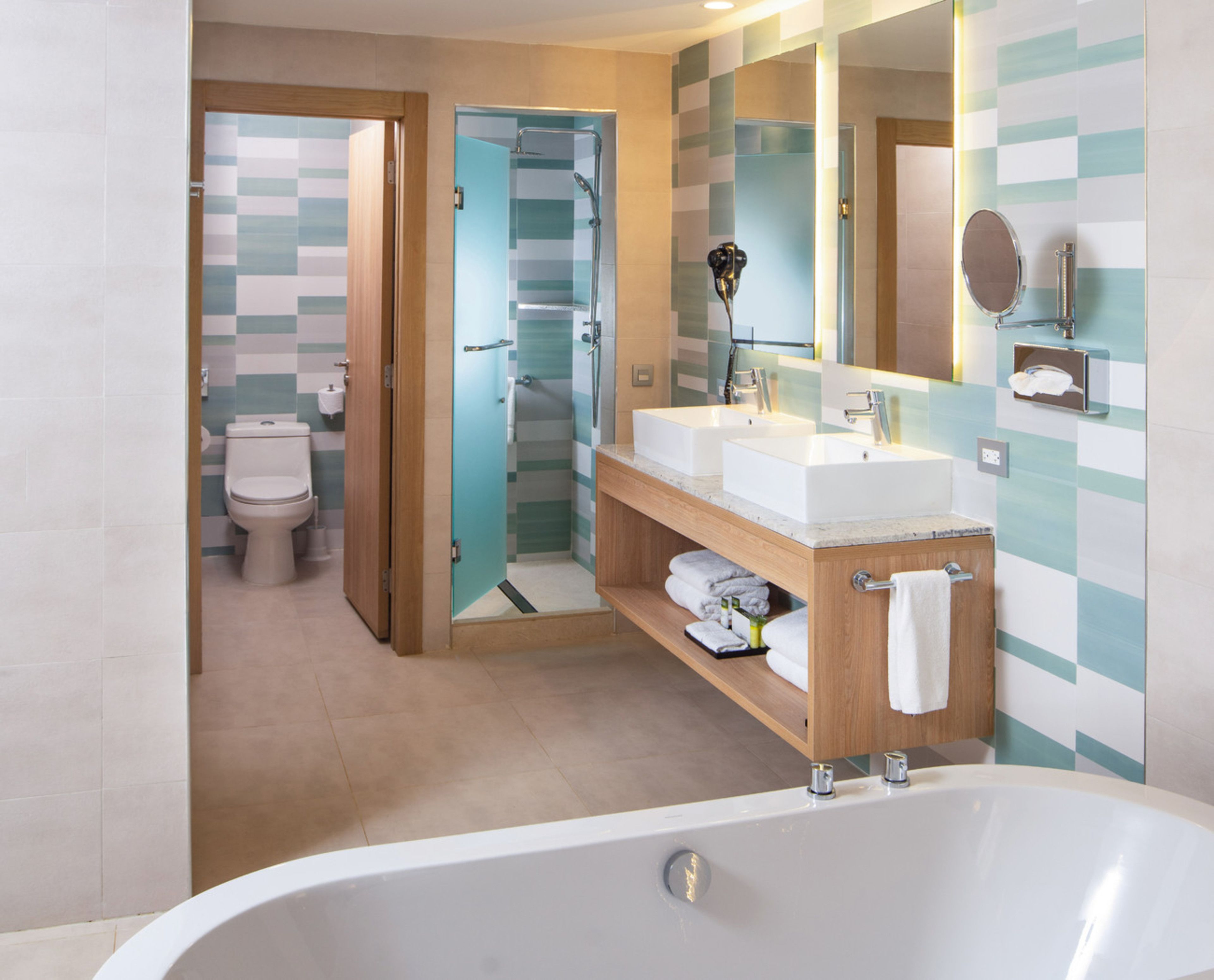 Un baño moderno con bañera, dos lavamanos, ducha e inodoro.