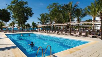 Relax by the pool surrounded by palm trees and lounge chairs.