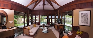A spacious living area with a large window overlooking a pool, furnished with a sofa, chairs, and a coffee table.