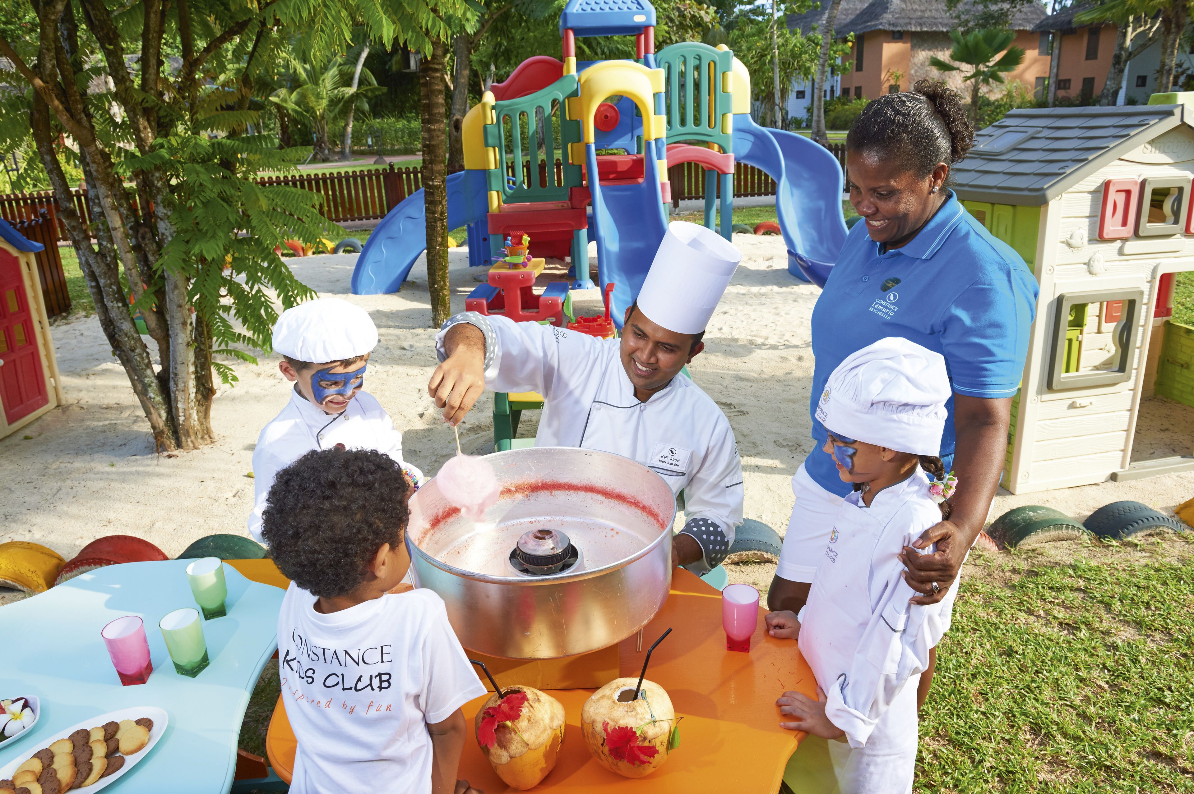 A group of people at a playground with a large metal pot on a table.