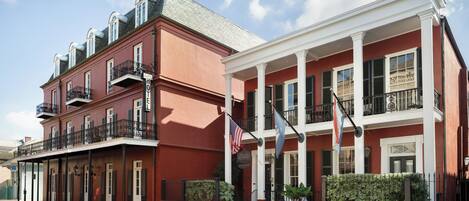 A two-story hotel with a red facade, white columns, and balconies.