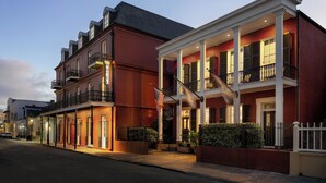 A hotel with a red facade, white columns, and balconies.
