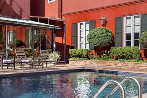 A pool area with lounge chairs and a covered seating area.