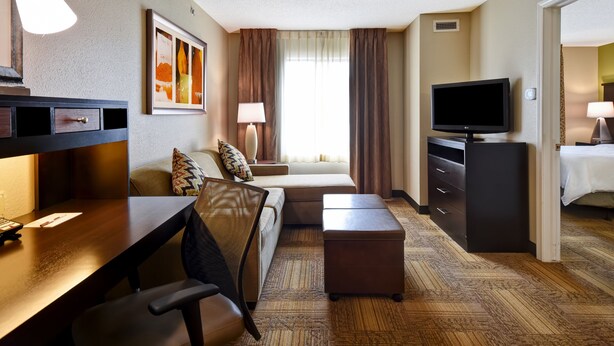 Een hotelkamer met een bureau, stoel, bank, televisie en een bed.