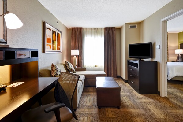 Une chambre d’hôtel équipée d’un bureau, d’une chaise, d’un canapé, d’une télévision et d’un lit.