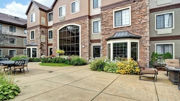 A multi-story residential building with a patio area featuring outdoor furniture and landscaping.