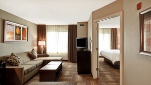 Een hotelkamer met een bank, een televisie, een bureau en een bed.
