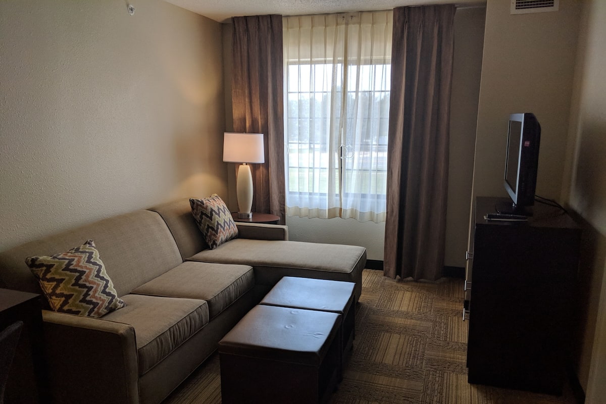Een hotelkamer met een bank, een tafeltje, een televisie en een lamp.