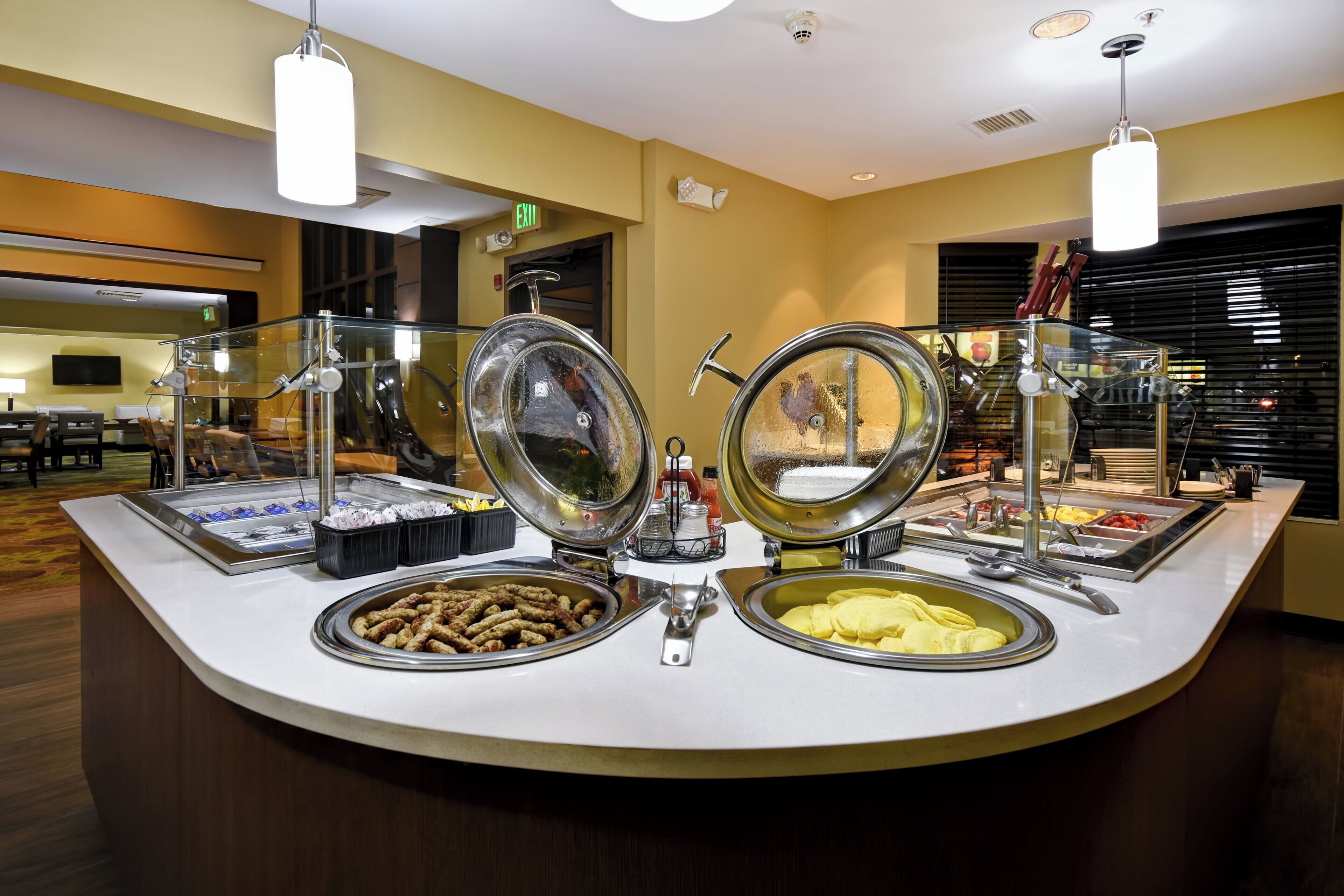 A buffet counter with various food items and a glass partition.