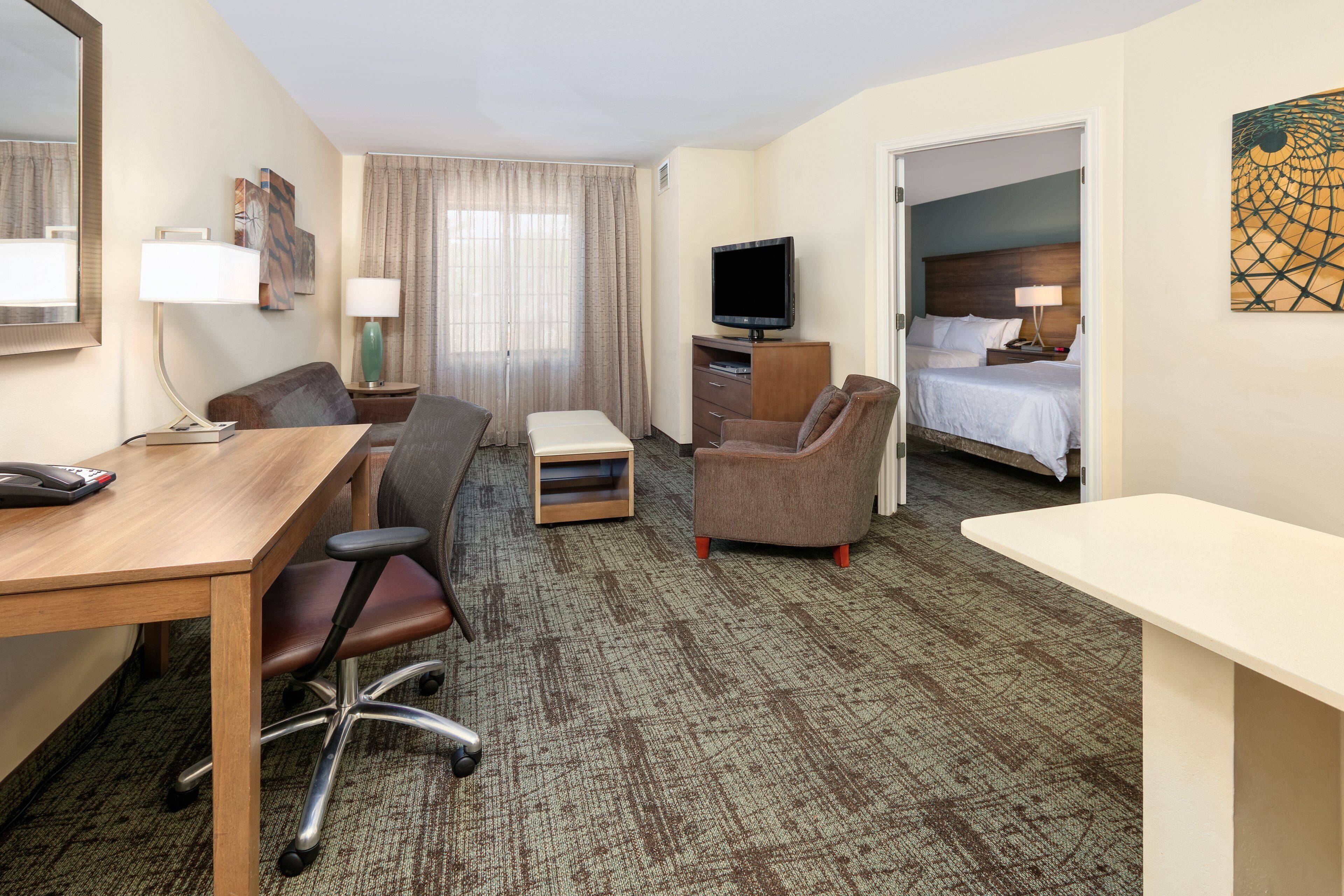 A hotel room with a desk, office chair, sofa, and a bed.