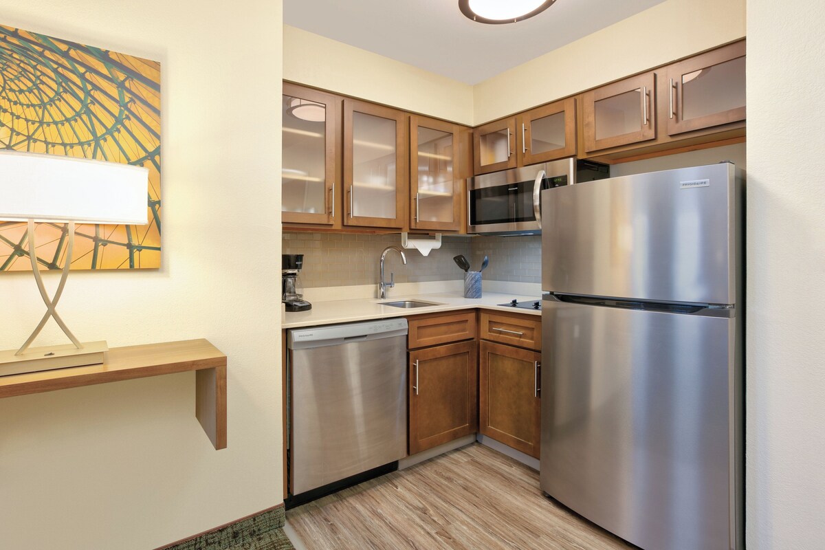 A modern kitchen with wooden cabinets, stainless steel appliances, and a dishwasher.