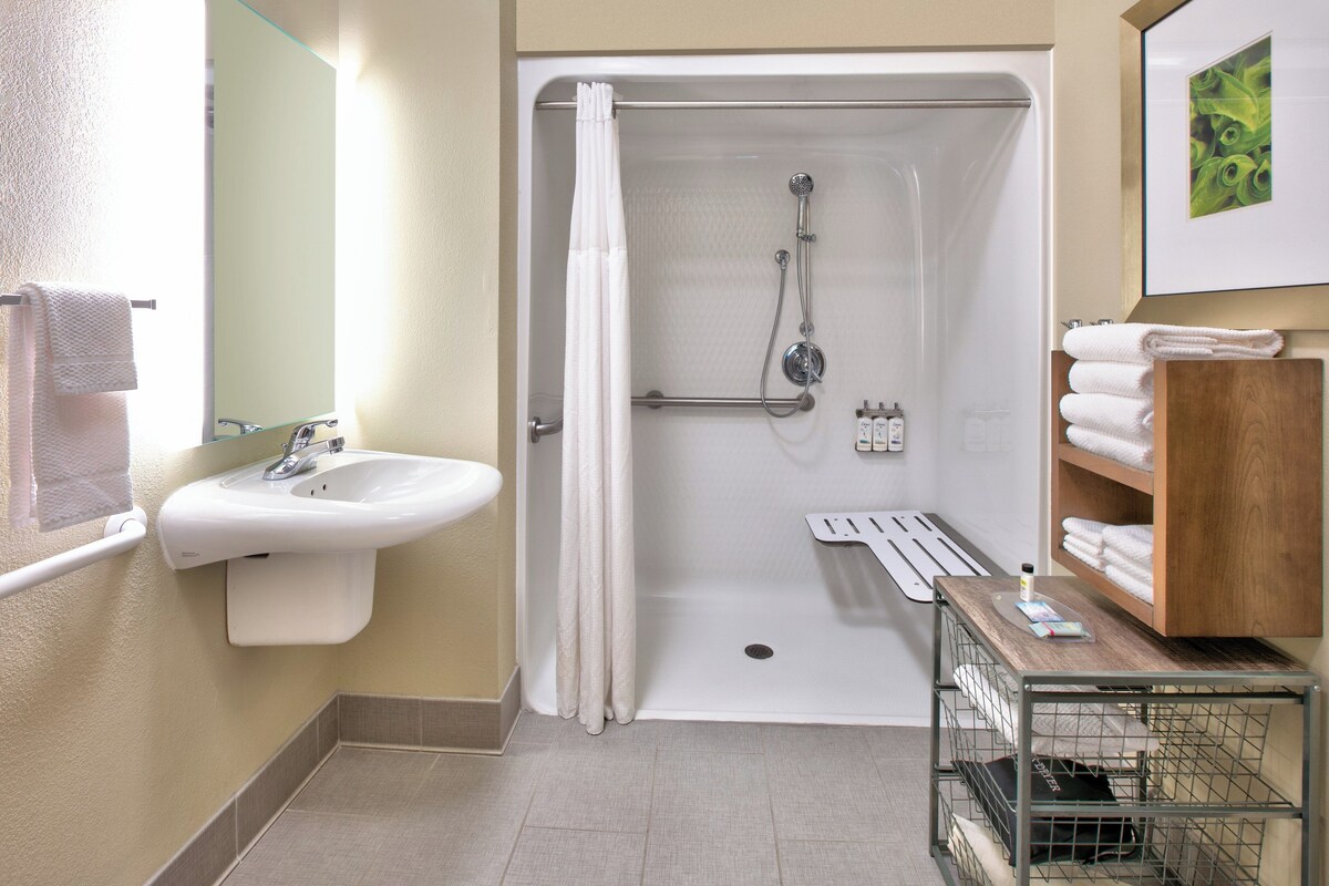 A bathroom with a shower, sink, and a towel rack.
