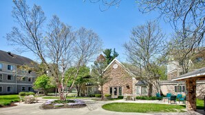 A residential area with a stone building, a lawn, and outdoor seating. - Staybridge Suites Corning by IHG (Corning)
