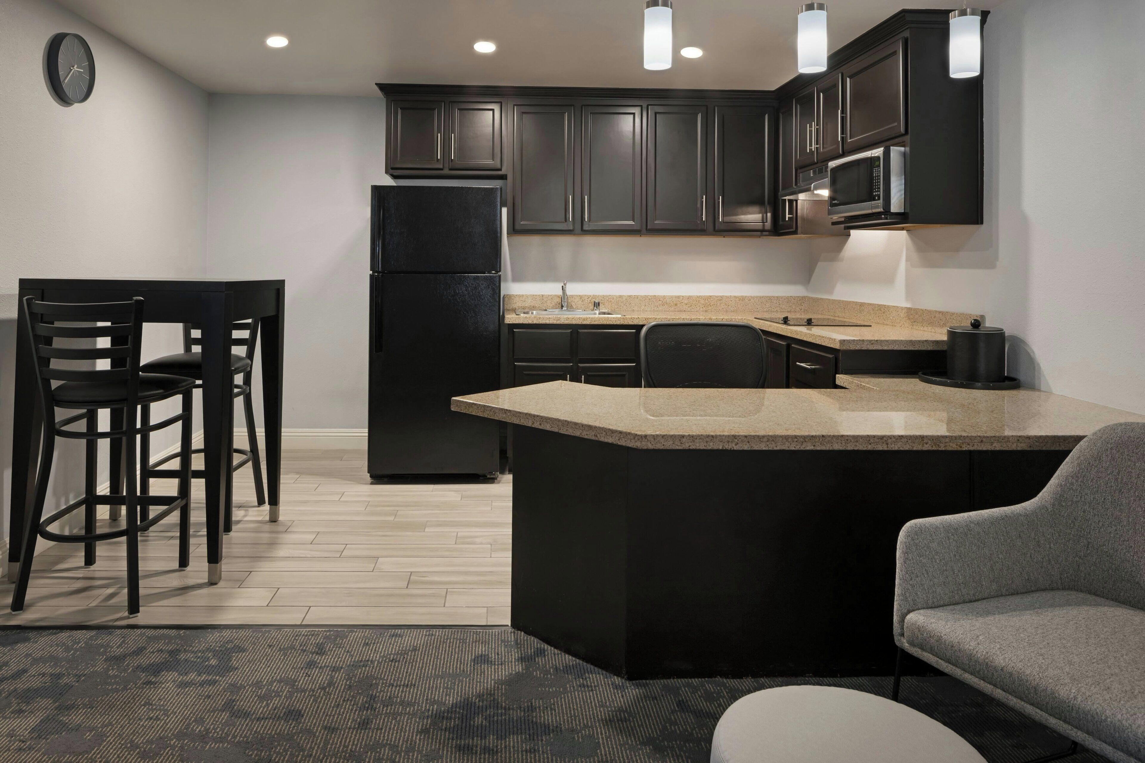 A modern kitchen with dark cabinets, a central island, and a microwave above the counter.