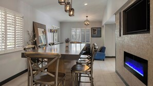 A modern kitchen with a large island, bar stools, pendant lighting, and a built-in TV. - City Express By Marriott Manhattan Beach (Manhattan Beach)