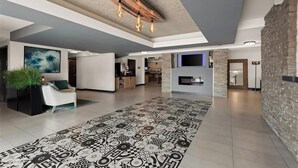 A spacious living area with a patterned rug, a fireplace, and a stone wall. - City Express By Marriott Manhattan Beach (Manhattan Beach)