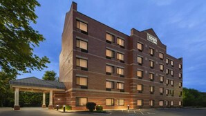 A multi-story hotel with a brick facade, a covered entrance, and a parking lot.