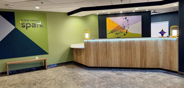 A reception area with a wooden reception desk, a bench, and a wall with a 'spark' sign.