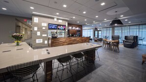 A modern hotel lobby with a long reception desk, bar area, seating, and large windows. - Courtyard by Marriott Russellville (Russellville)