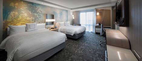 A hotel room with two beds, a desk, a chair, a TV, and a large window.