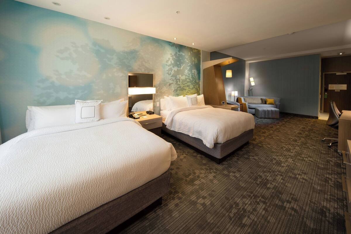 Ein Hotelzimmer mit zwei Betten, einem Schreibtisch und einem Stuhl.