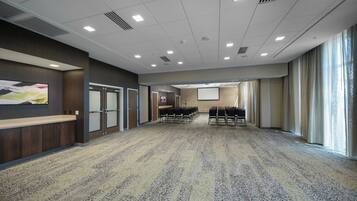 A conference room with a carpeted floor, a large screen, and a long table with chairs.