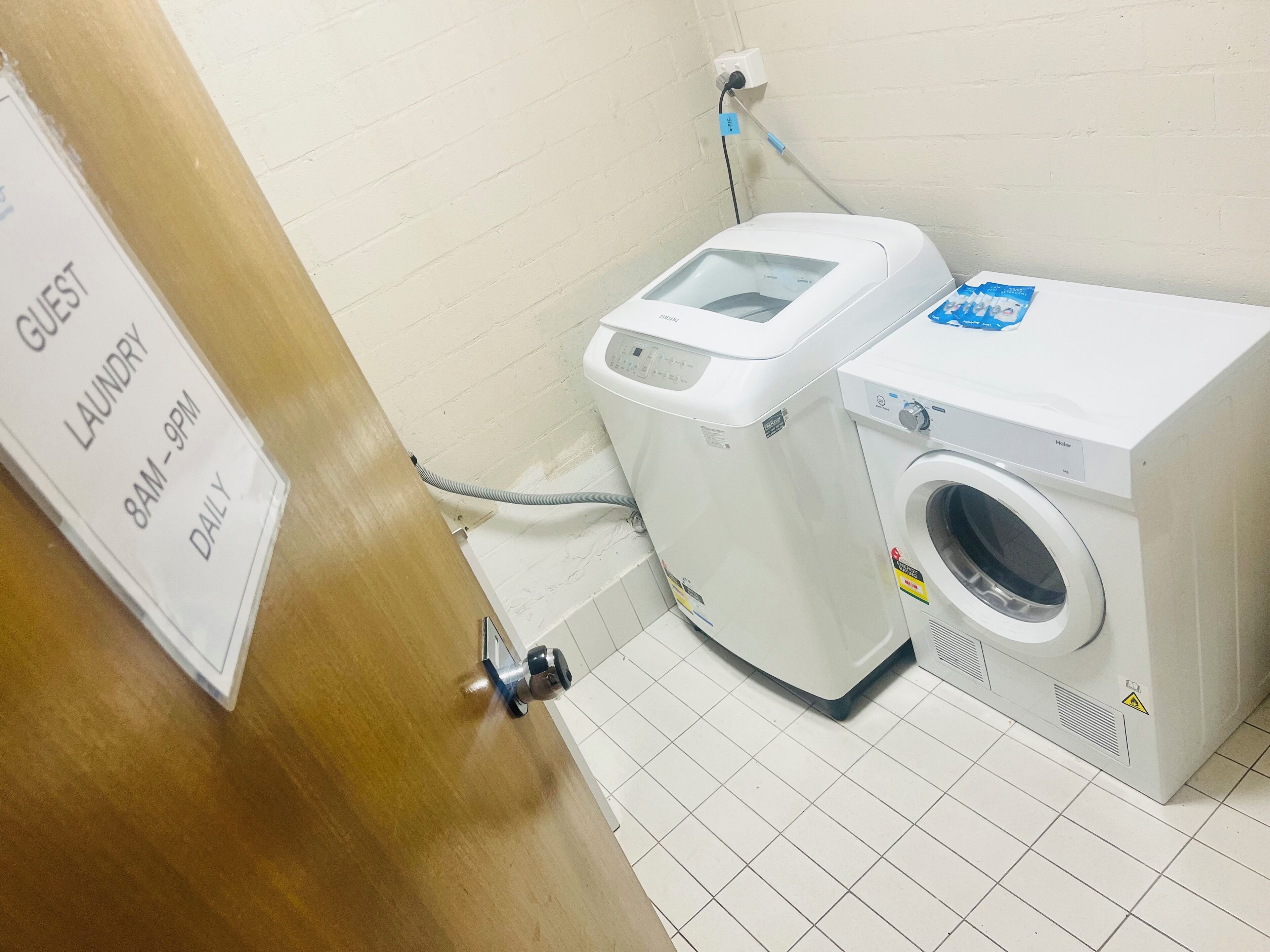 A laundry area with a sign indicating guest laundry hours from 8 AM to 9 PM daily.