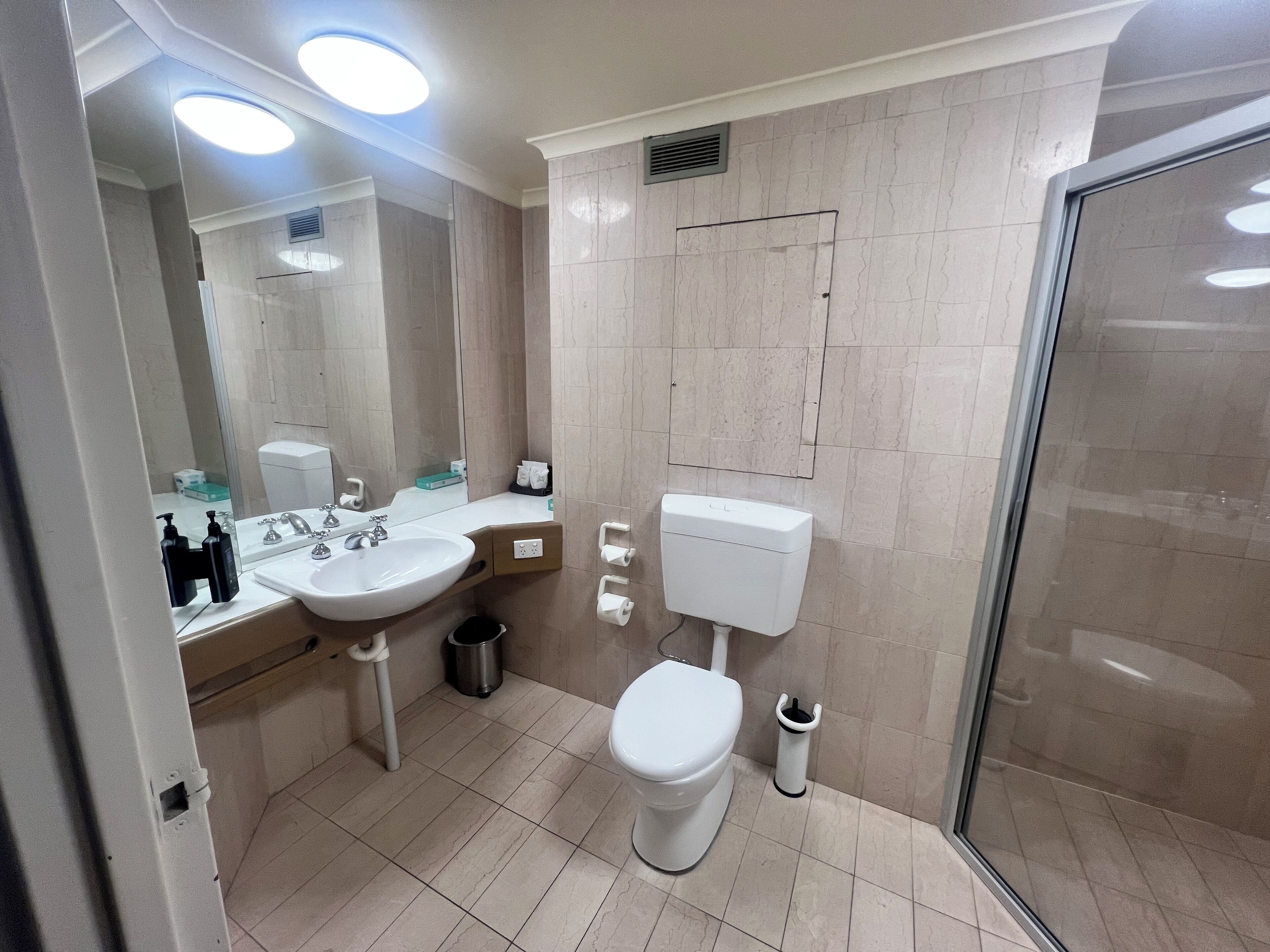 Et moderne badeværelse med vask, toilet og bruser.
