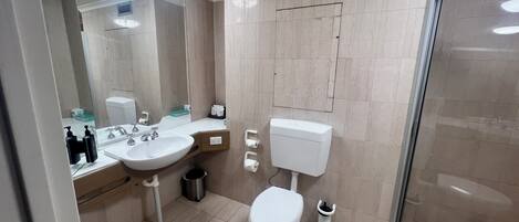Une salle de bain moderne équipée d’un lavabo, de toilettes et d’une douche.