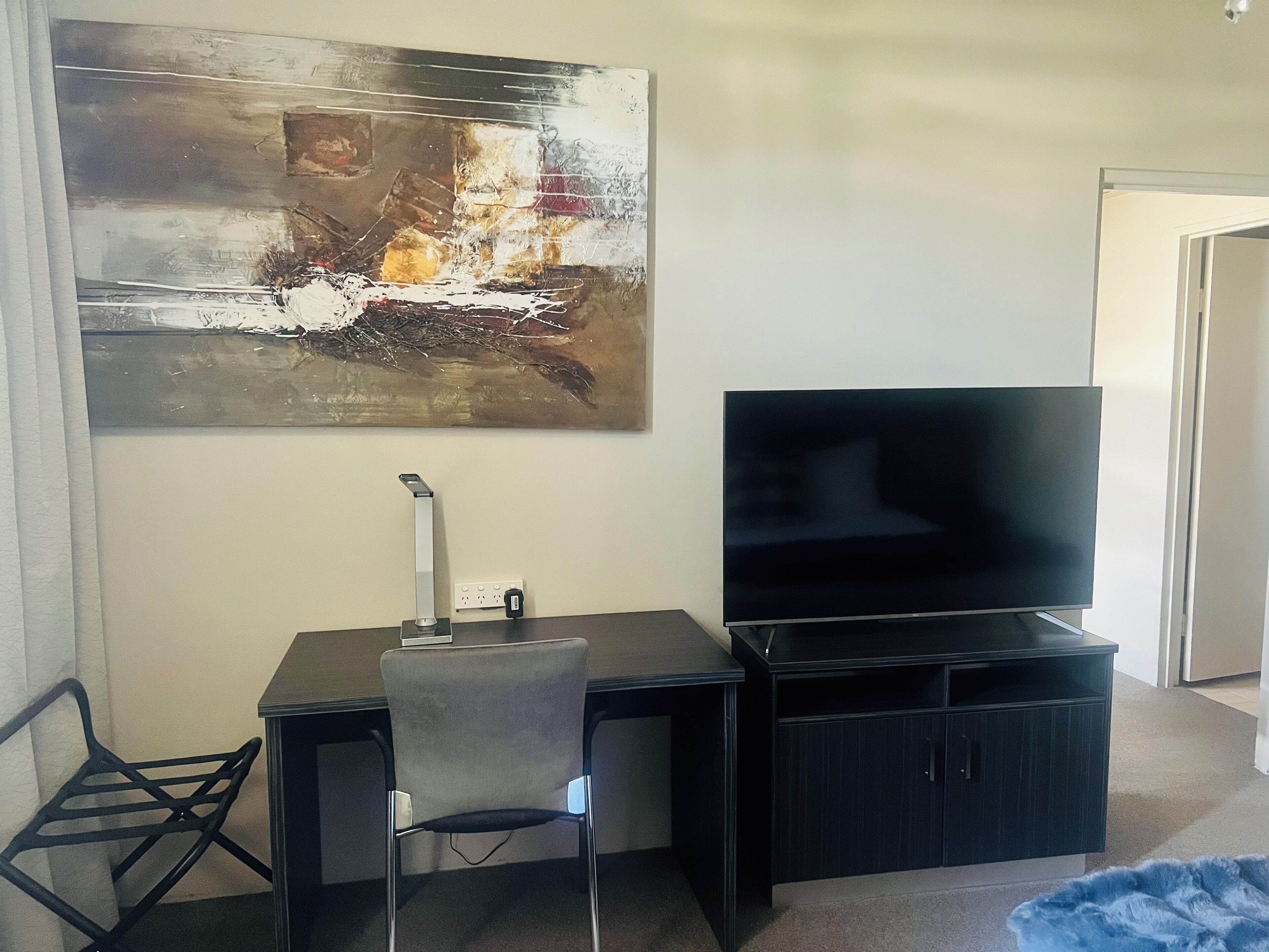 Een moderne woonkamer met een flatscreen televisie, een bureau en een stoel.