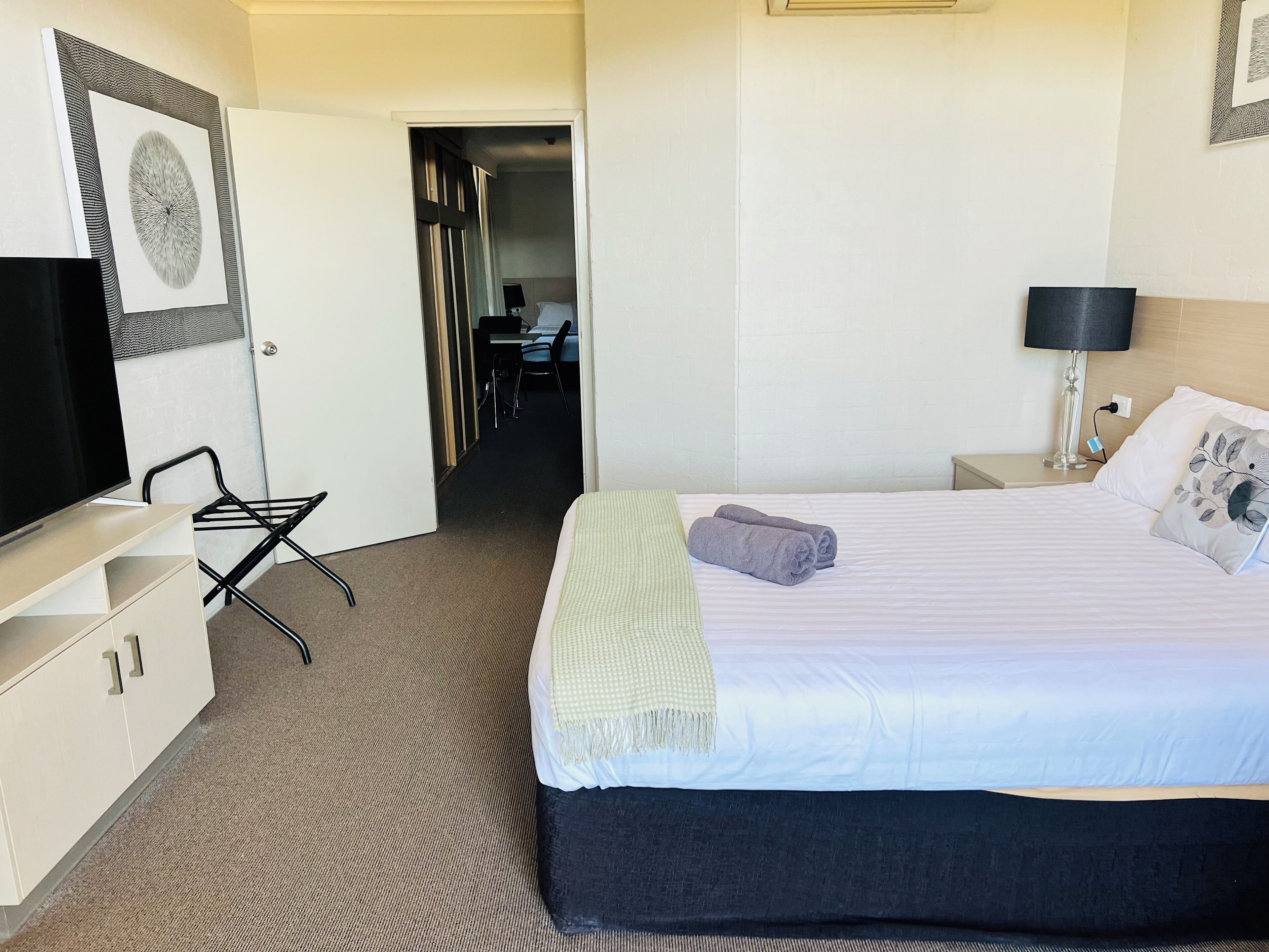 A hotel room with a bed, a TV, a desk, and a chair.