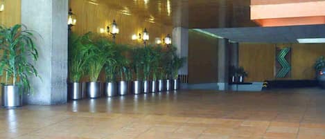 Un vestíbulo amplio con piso de baldosas, plantas en macetas y techo de madera.
