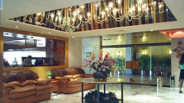 A lobby with a seating area, a chandelier, and a reception desk. - Segovia Regency Hotel (Mexico City)