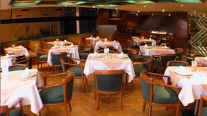 A dining area with multiple tables and chairs, arranged in a spacious layout. - Segovia Regency Hotel (Mexico City)