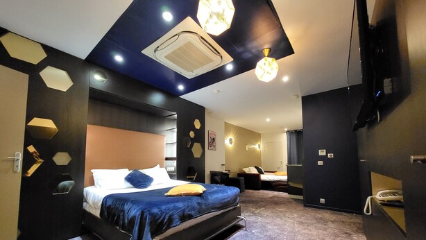 A modern bedroom with a bed, a desk, and a shower area.