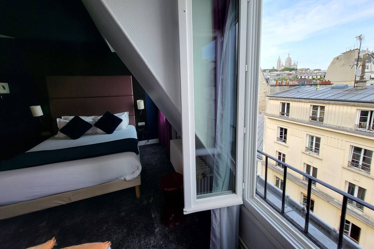 Une chambre d’hôtel avec un lit, une fenêtre et une vue sur les bâtiments de la ville.