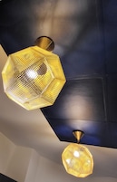 Two hexagonal pendant lights with a honeycomb pattern, hanging from a dark ceiling.
