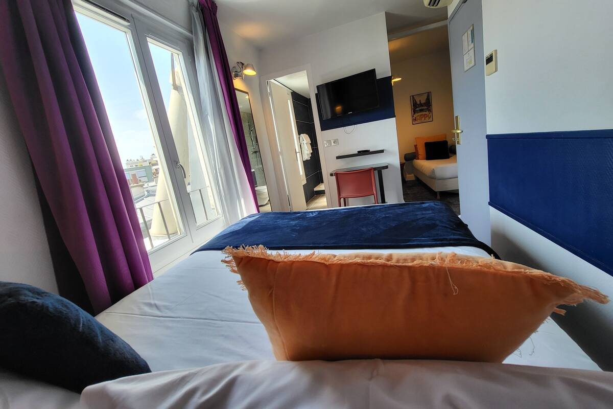Une chambre d’hôtel avec un lit, un bureau, une télévision et une vue sur la ville.